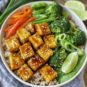 - 1 block firm tofu - 1/4 cup cornstarch - 2 tablespoons vegetable oil - 1 cup cooked brown rice - 1 cup broccoli florets - 1 cup snap peas - 1 medium carrot, julienned - 1 red bell pepper, sliced into thin strips - 1/4 cup teriyaki sauce - 1 tablespoon sesame seeds - 2 green onions, sliced thinly - Optional: lime wedges for serving This recipe for crispy teriyaki tofu bowls highlights delicious flavors and fresh veggies. You start with firm tofu because it holds its shape well when cooked. Make sure to press and drain it thoroughly before cooking. This step removes extra moisture and helps achieve that perfect crunch. Next, you coat the tofu cubes in cornstarch. This coating is key for creating a crispy exterior. The cornstarch absorbs moisture and forms a crunchy crust when you sauté the tofu. For the veggies, I love using broccoli, snap peas, carrots, and red bell pepper. These not only add color but also provide a mix of textures and flavors. They pair wonderfully with the savory teriyaki sauce. Speaking of the sauce, you can use store-bought teriyaki sauce for ease or make your own at home. Either way, the sauce adds a sweet and salty kick to the dish. Adding sesame seeds and sliced green onions on top gives the bowls a nice finish. If you want a bit of zing, serve lime wedges on the side. For the full recipe, refer to the earlier section. Enjoy making these tasty crispy teriyaki tofu bowls! Start by pressing the tofu. This step removes extra moisture. Slice the tofu into bite-sized cubes. I like to use a sharp knife for clean cuts. Next, coat the tofu. Sprinkle cornstarch over the cubes in a bowl. Toss the tofu gently until each piece is coated. This coating helps achieve a crispy texture when cooking. Heat vegetable oil in a large non-stick skillet. Use medium-high heat for the perfect crisp. Once hot, add the tofu. Cook for about 8-10 minutes. Turn the cubes to cook evenly. Watch for a golden-brown color on all sides. This is how you get that crunch that everyone loves. While the tofu cooks, steam the broccoli and snap peas. Use a steamer basket over boiling water. Steam for about 3-4 minutes. You want the veggies to be bright and tender-crisp. This keeps their color and nutrients intact. For added crunch, prepare other vegetables like carrots and bell peppers as you go. Once the tofu is crispy, lower the heat. Pour teriyaki sauce over the tofu. Stir gently to coat each piece. Allow it to cook for 1-2 more minutes. This gives the sauce time to thicken and stick to the tofu. The flavor will be rich and delicious. In each serving bowl, start with a layer of brown rice. Top it with the crispy teriyaki tofu. Add the steamed broccoli, snap peas, julienned carrots, and red bell pepper slices. The colors will make your dish pop. Finally, garnish with sesame seeds and sliced green onions. This adds a nice touch and extra flavor. For an optional zest, serve lime wedges on the side. For the full recipe, check out [Full Recipe]. To make your tofu crispy, drying is key. After pressing the tofu, pat it dry well. This helps remove extra moisture. Less moisture means a better fry and a crispier texture. The oil temperature matters too. Heat your vegetable oil over medium-high heat. If the oil is too cool, the tofu will soak up oil instead of becoming crispy. A good test is to drop a small piece of tofu in the oil. If it sizzles, you're ready to fry. To make your teriyaki tofu even tastier, consider adding spices or marinades. You can sprinkle garlic powder or ginger for extra flavor. Marinating the tofu for at least 15 minutes can also deepen its taste. Choosing the right teriyaki sauce is crucial. You can buy sauce or make your own for a fresher taste. A sauce with a balance of sweet and salty works best. Look for options with natural ingredients for a healthier dish. When serving your teriyaki tofu, pair it with sides that complement the dish. Steamed rice works great, but you can also try quinoa for a nutty flavor. Adding a side salad can enhance the meal's freshness. You can customize your bowl to fit your tastes. Try swapping out vegetables based on what you like. Add more crunch with sliced radishes or extra color with yellow bell peppers. Enjoy the freedom to make it your own! For the full recipe, refer to the section above. {{image_4}} If you want to switch up the protein, tofu isn’t your only choice. You can use chicken or tempeh instead. Both options add great flavor and texture. For chicken, choose boneless, skinless thighs for juiciness. Cut them into bite-sized pieces and cook them like the tofu. Tempeh, made from fermented soybeans, offers a nutty taste. Simply slice it and coat it in cornstarch, just like the tofu. You can make your bowls even better with seasonal veggies. In spring, try asparagus or green beans. In summer, add zucchini or bell peppers. Fall offers butternut squash or Brussels sprouts. You can also mix in leafy greens like spinach or kale. They add nutrients and a vibrant color. Mushrooms are another great choice. They bring umami and a meaty bite. While store-bought teriyaki sauce is tasty, making your own is fun and easy. Combine soy sauce, honey, garlic, and ginger for a fresh taste. Simmer it until it thickens. Other sauces can work too. Try a spicy chili sauce for heat or a peanut sauce for creaminess. Each option brings its own unique flavor to your crispy tofu bowls. For the full recipe, check out the Crispy Teriyaki Tofu Bowls. To store your leftover crispy teriyaki tofu bowls, place them in an airtight container. Make sure the bowl cools down to room temperature before sealing it. This helps keep the tofu crispy and the veggies fresh. You can store these bowls in the fridge for up to three days. If you plan to enjoy them later, it's best to keep the sauce separate until you're ready to eat. For the best texture when reheating, use an oven or a skillet. Preheat your oven to 350°F (175°C) and place the tofu bowls on a baking sheet. Heat for about 10 to 15 minutes until warmed through. If using a skillet, add a splash of water to prevent sticking and cover it. This method helps retain the crispiness of the tofu and keeps the veggies tender. You can freeze these tofu bowls for later use. To do this, let the bowls cool completely. Place the tofu and veggies in a freezer-safe container. Avoid freezing the rice, as it can become mushy. These bowls can last up to three months in the freezer. When you're ready to enjoy them, thaw in the fridge overnight and reheat using the methods above. To make tofu crispy, follow these key steps: - Press the tofu: Remove as much water as you can. - Cube the tofu: Cut it into even, bite-sized pieces. - Dry the tofu: Pat each piece with a paper towel. - Coat with cornstarch: Sprinkle cornstarch evenly over the tofu. - Heat the oil: Use a hot skillet with vegetable oil. - Cook until golden: Sauté the tofu for about 8-10 minutes, turning it often. These steps help create a crispy texture that you will love. Yes, you can easily make this dish vegan. Here are some simple swaps: - Use plant-based teriyaki sauce: Check labels for non-vegan ingredients. - Add more vegetables: Use any fresh veggies you enjoy. - Try different grains: Substitute brown rice with quinoa or farro. These changes keep the dish tasty and vegan-friendly. Store your leftover teriyaki tofu bowls with these tips: - Use airtight containers: Keep air out to maintain freshness. - Refrigerate: Store in the fridge for up to 3 days. - Separate the sauce: Keep the sauce separate to avoid sogginess. These steps help retain taste and texture. Serve your teriyaki bowls in an eye-catching way. Here are some ideas: - Layer the ingredients: Start with a base of rice, then tofu, and veggies on top. - Garnish well: Add sesame seeds and green onions for flair. - Use lime wedges: Serve with lime on the side for a zesty kick. These tips make your dish look appealing and delicious. You can find the full recipe [here](#). This guide covered making teriyaki tofu bowls from start to finish. You learned about key ingredients and how to prepare everything for a tasty meal. We shared tips for crispy tofu and ideas for variations. Remember, adjust the dish to fit your taste and enjoy it fresh or stored for later. This meal is healthy, fun, and easy to customize. Dive in and have fun cooking!