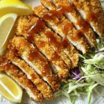 - 2 boneless chicken breasts - 1 cup panko bread crumbs - 1/2 cup all-purpose flour - 1 teaspoon garlic powder - 1 teaspoon onion powder - 1 teaspoon paprika - Salt and pepper to taste - 2 large eggs, beaten - Cooking spray - Tonkatsu sauce (for drizzling) - Shredded cabbage (for garnish) - Lemon wedges (for squeezing) The main ingredients for this dish are simple but important. Start with boneless chicken breasts. They are easy to work with and cook evenly. Panko bread crumbs give that special crunch. They are lighter and crispier than regular bread crumbs. All-purpose flour acts as the base layer, making it easier for the coating to stick. For seasonings, garlic powder, onion powder, and paprika add great flavor. They make each bite tasty. Don’t forget salt and pepper; they enhance all the other flavors. You will also need eggs for the egg wash. They help the panko stick nicely. Cooking spray is a must to help crisp the chicken in the air fryer. Tonkatsu sauce is the star of the show when serving. It’s sweet, tangy, and oh-so-delicious. Shredded cabbage adds a nice crunch and freshness. Finally, lemon wedges bring a zesty kick when squeezed over the chicken. Gather these ingredients before you start cooking. Each one plays a role in making your Air Fryer Chicken Katsu crunchy and flavorful. To start, you need to ensure your chicken breasts are even. If they are thick, slice each breast in half. This creates thinner cutlets. Next, place each cutlet between two sheets of plastic wrap. Use a meat mallet to pound them gently. Aim for about 1/2 inch thick. This helps the chicken cook evenly. Now, let’s prepare the dredging stations. In a shallow dish, mix the all-purpose flour with garlic powder, onion powder, paprika, salt, and pepper. Make sure to combine it well. In another shallow dish, whisk the eggs lightly. This adds air and helps the panko stick. In the third dish, add the panko bread crumbs. Season them with a pinch of salt and pepper. Take each chicken cutlet and dredge it in the flour mixture. Shake off any excess flour. Next, dip it into the beaten eggs. Ensure it’s fully coated. Finally, press the chicken into the panko breadcrumbs. Make sure to cover both sides for a nice crunch. Preheat your air fryer to 400°F (200°C). Run it for about 5 minutes. Lightly spray the basket with cooking spray. This helps prevent sticking. Carefully arrange the breaded chicken cutlets in a single layer in the basket. Avoid overcrowding. Lightly spray the tops with more cooking spray. Cook the cutlets for about 10-12 minutes. Flip them halfway to achieve an even golden brown. The chicken should reach an internal temperature of 165°F (74°C). Once the chicken katsu is done, remove it from the air fryer. Let it rest for about a minute. This helps the juices stay in the meat. After resting, slice it into strips for serving. To get that perfect crunch, panko breading is key. Panko is lighter and crispier than regular breadcrumbs. This gives your chicken katsu a nice, crunchy texture. When you coat the chicken, make sure to cover every inch. Use cooking spray on top of the breaded chicken before frying. This helps it get extra crispy while cooking. To make your chicken katsu burst with flavor, enhance the flour mixture. Add more spices like cayenne for heat or dried herbs for depth. You can also mix in some Parmesan cheese for extra richness. For serving, drizzle tonkatsu sauce generously over the chicken. It adds a sweet and tangy touch. Pair it with fresh, shredded cabbage for crunch and a squeeze of lemon for brightness. Cooking time can change based on the size of your chicken pieces. Thicker pieces need more time to cook through. Always check the internal temperature. Your chicken should reach 165°F (74°C) for safe eating. If it’s not done, return it to the air fryer for a few more minutes. {{image_4}} You can swap chicken for pork if you prefer. Pork katsu has a rich flavor. Use pork loin or tenderloin for best results. For a vegetarian twist, try eggplant or tofu. Slice them thin, then follow the same coating steps. This way, you can enjoy a crispy texture without meat. Mix it up by adding spices to the flour. Try cayenne for heat or thyme for an earthy taste. This will give your katsu a unique twist. When it comes to sauces, tonkatsu is a classic, but don’t stop there. You can serve it with BBQ sauce or sweet chili sauce for something different. Each sauce brings its own flavor. Pair your chicken katsu with fresh vegetables. Steamed broccoli or carrots work great. They add color and nutrition to your meal. Rice is a popular choice. White rice or fried rice complement the katsu well. Noodles can also be a tasty option. Try soba or udon for a delightful meal. After you enjoy your air fryer chicken katsu, store the leftovers in the fridge. Place the chicken in an airtight container. This helps keep it fresh. Use it within three days for the best taste. If you want to keep chicken katsu longer, freezing is a good option. Wrap each piece tightly in plastic wrap, then place them in a freezer bag. This prevents freezer burn. You can freeze the chicken katsu for up to three months. To reheat the chicken, first, thaw it overnight in the fridge. Preheat your air fryer to 375°F (190°C). Heat the chicken for about 8-10 minutes until it is warm and crispy again. To keep the texture of chicken katsu when storing, avoid stacking the pieces. Stacking can make them soggy. Instead, lay them flat in a single layer. When reheating, use a light spray of cooking oil to maintain crunchiness. Chicken katsu is a Japanese dish made with breaded chicken. You coat the chicken with flour, dip it in egg, and then cover it with panko breadcrumbs. This process gives the chicken a crispy texture. Traditionally, you serve it with tonkatsu sauce and shredded cabbage. Yes, you can use frozen chicken. Just make sure to thaw it first. You want the chicken to be evenly cooked. Thaw it in the fridge overnight or use the microwave for a quick thaw. Chicken katsu can be a part of a healthy meal. It uses chicken breast, which is lean. However, it is fried or air-fried, so be mindful of portion sizes and sauces. Pair it with veggies for a balanced dish. You can use regular breadcrumbs if you don't have panko. They may not be as crunchy, but they will work. Crushed cornflakes or crushed crackers can also add crunch and flavor. The chicken is done when it reaches an internal temperature of 165°F (74°C). You can use a meat thermometer to check. The outside should be golden brown and crispy. If it looks undercooked, give it more time in the air fryer. In this article, we explored making delicious chicken katsu. I broke it down into simple steps for you. We discussed the key ingredients, special tips, and various options. Remember, achieving that perfect crunch comes from using panko and cooking spray. Feel free to mix flavors and try different proteins too. Store leftovers properly to keep them tasty. Enjoy your cooking and impress friends and family with your chicken katsu!